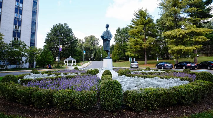 Statue in garden with colorful flowers and greenery.