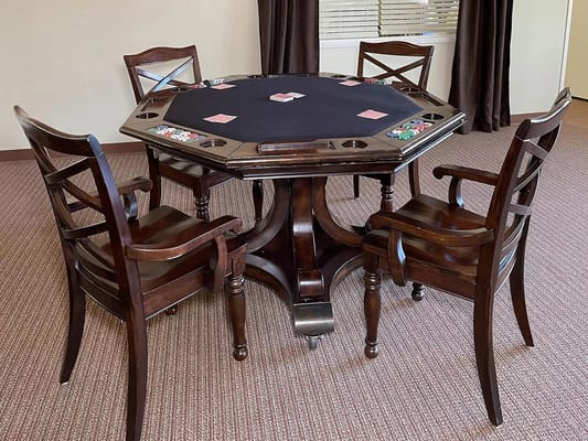 Octagonal gaming table with cards and chips surrounded by wooden chairs