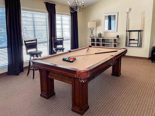 A cozy pool table room with seating and natural light