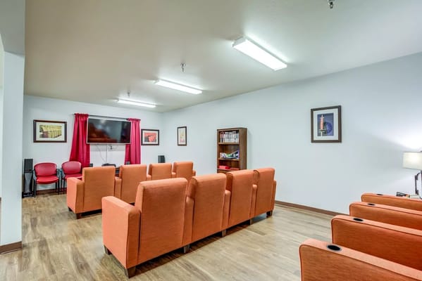 Spacious lounge area with orange chairs and a TV