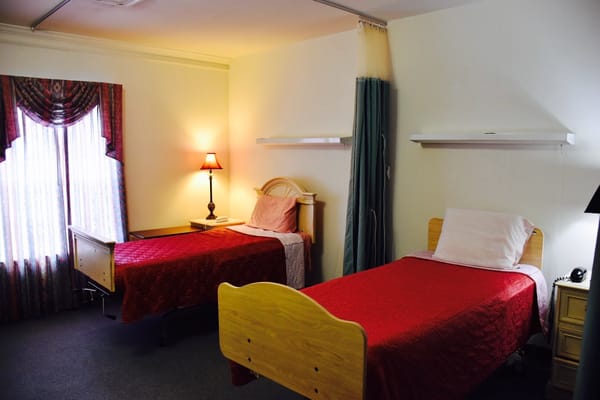 Two twin beds with red bedding in a private room.
