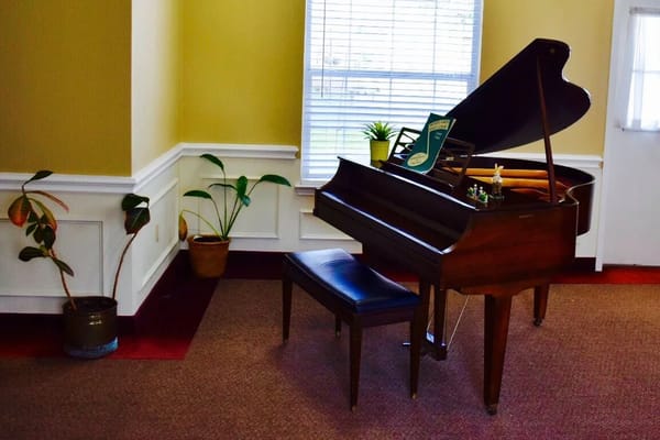 A wooden piano with a bench in a cozy room