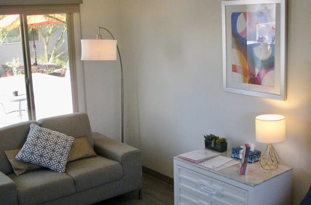 A cozy living room with a couch, lamp, and coffee table in Stonewall Gardens Assisted Living.