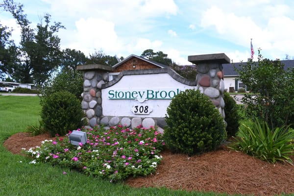 Sign for Stoneybrook Memory Care Home with flowers and greenery