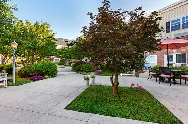 A peaceful courtyard with green plants, seating areas, and decorative flamingos.