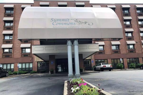 Front entrance of Summit Commons with a canopy and flower beds