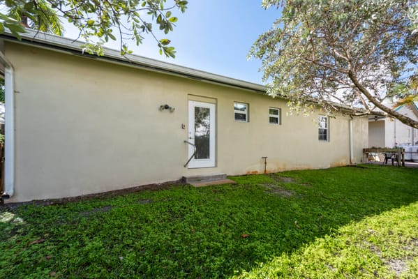 View of the backyard at Sunny Days Assisted Living showing green grass and a side entrance.