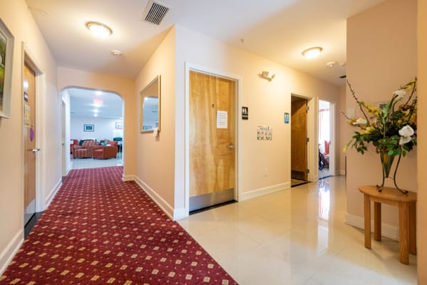 Hallway with rooms leading to a common area in Sunny Days Assisted Living.