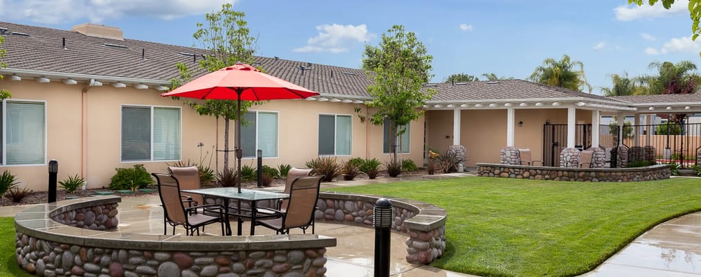 Patio with seating and an umbrella in a senior living community