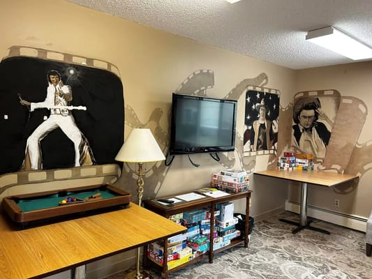 Interior of an activity room featuring film-themed murals and a pool table.
