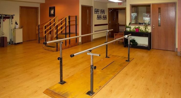 Therapy room with parallel bars and wooden flooring
