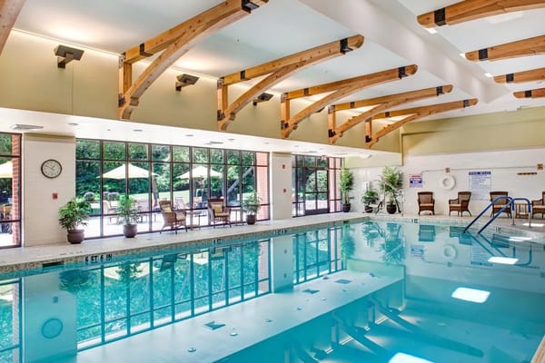 Well-lit indoor pool area with wooden beams and seating