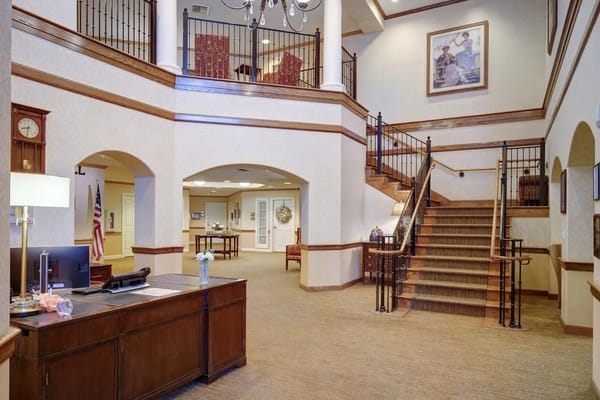 Spacious lobby with wooden reception desk and staircase.