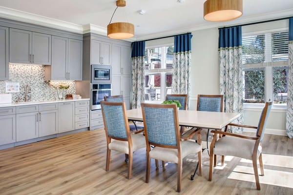Bright dining area with a large table and modern kitchen appliances.