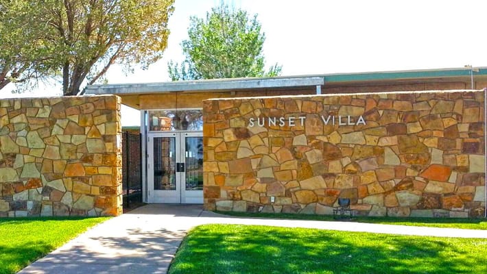 Entrance view of Sunset Villa Care Center with stone walls and glass doors