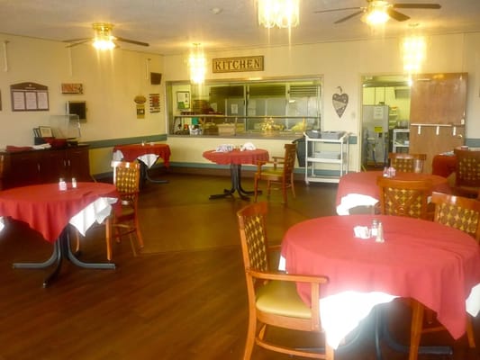 Dining room with red tablecloths and kitchen in the background