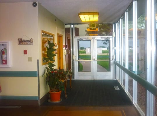 Entrance hallway with welcome sign and potted plant.