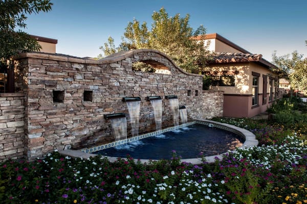 Water fountain with stone wall and colorful flowers