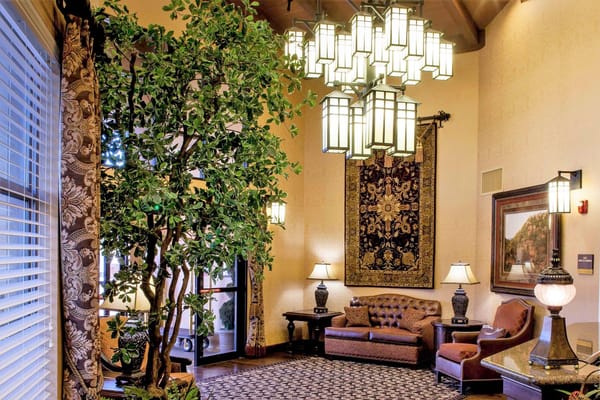 Cozy lobby with a large chandelier, plants, and comfortable seating.