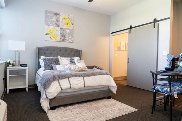 A well-decorated bedroom with a gray bed and floral artwork