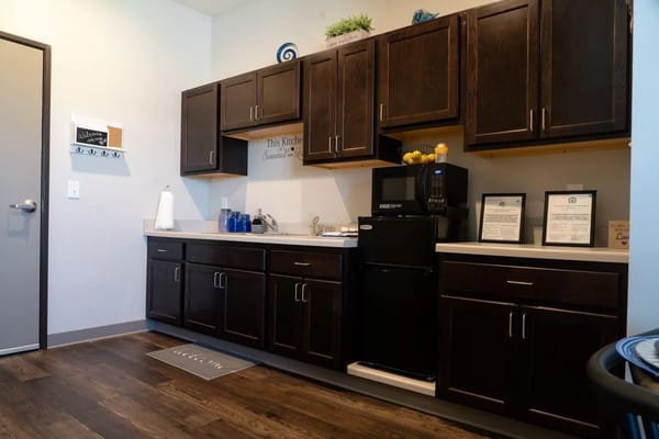A modern kitchenette featuring dark cabinets, a sink, and a microwave.