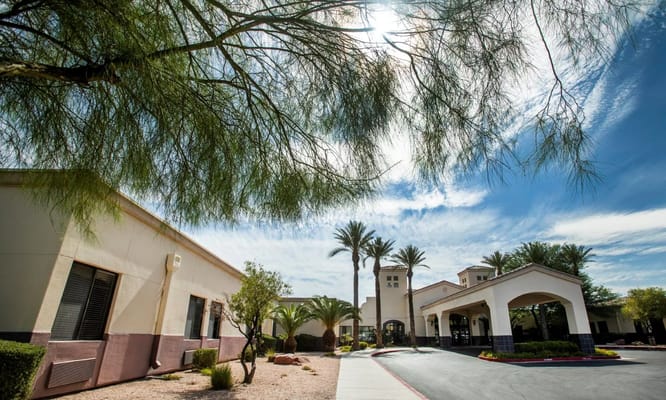Front entrance of TLC Care Center with palm trees and blue sky