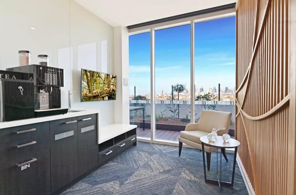 Cozy lounge area with a coffee machine and TV, overlooking the city skyline.