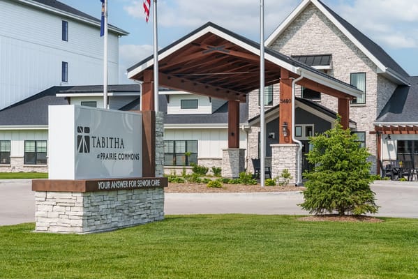 Entrance sign of Tabitha at Prairie Commons with flags