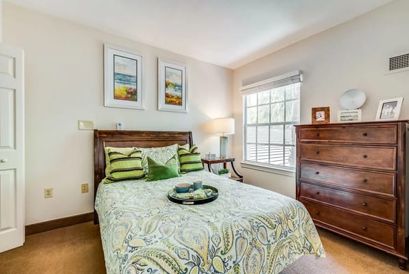 A well-decorated bedroom with a bed, bedside table, and dresser.