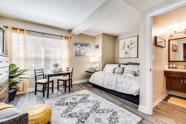 Spacious bedroom with a bed, dining table, and large window.