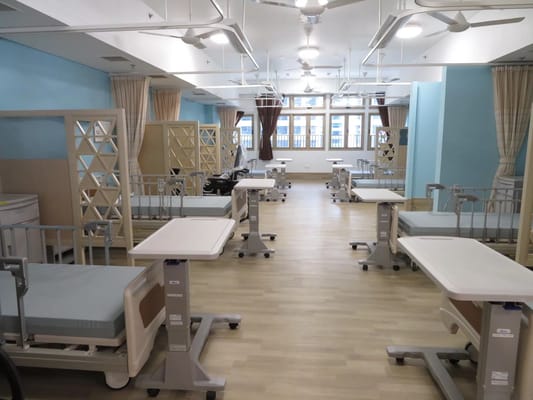 Interior of a patient room with beds and tables.