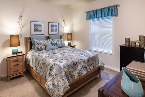 A well-decorated bedroom featuring a bed with a decorative blanket and bedside lamps.