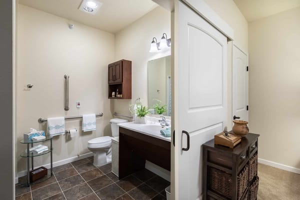 Well-lit bathroom with a sink, toilet, and storage