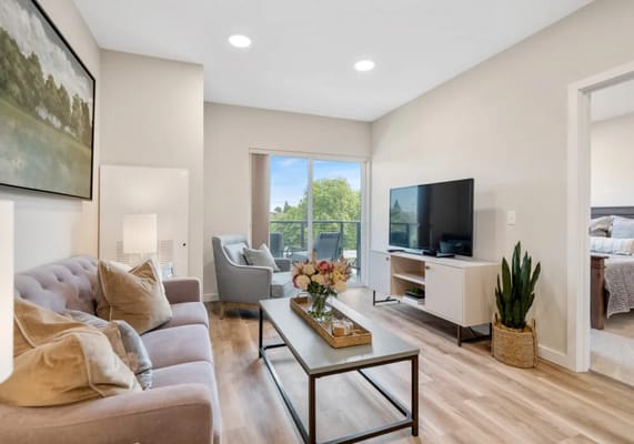 Bright and inviting living room with a sofa, TV, and balcony view