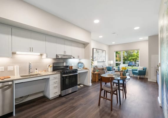 Modern kitchen and living area with dining table and seating in a senior living facility