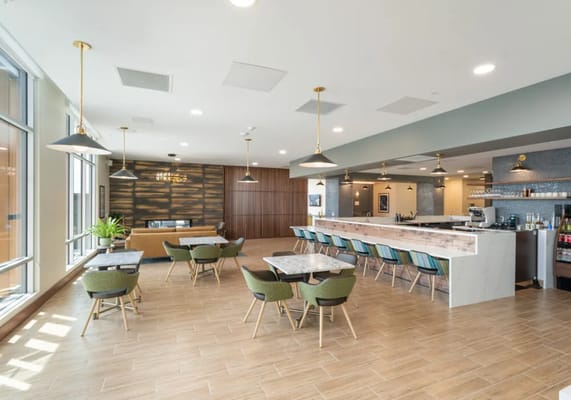 Spacious lounge area with tables and a bar at The Ackerly at Reed's Crossing