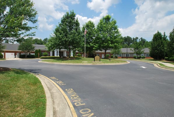 Entrance view of The Arboretum at Woodland Terrace with trees and a flag