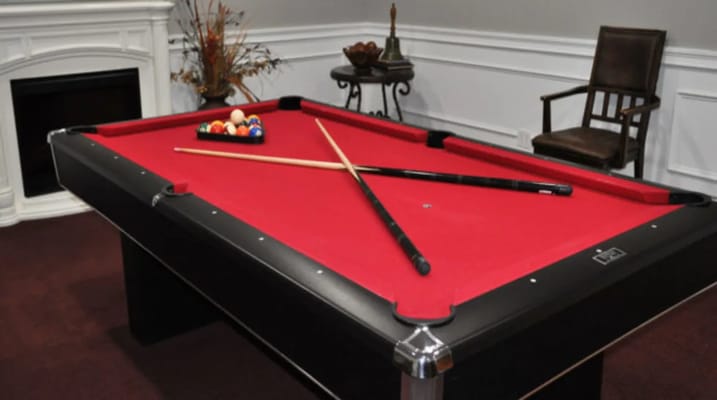Billiards table with red felt and cue sticks crossed