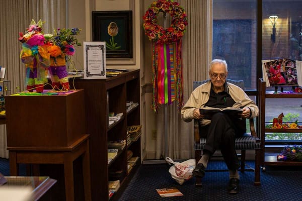 Elderly man reading a book in a decorated reading area