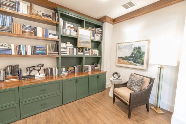 A reading nook featuring bookshelves, a chair, and a lamp.