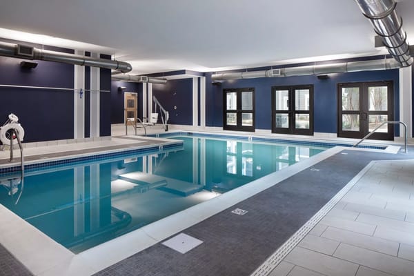 Indoor swimming pool with blue walls and poolside seating.