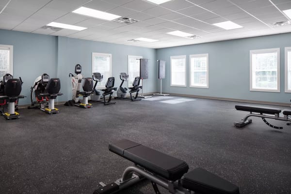 An equipped fitness center with various exercise machines and workout benches.