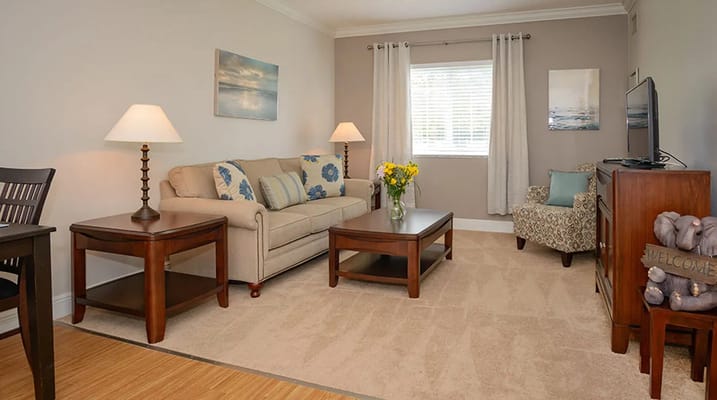 A cozy living room featuring a sofa, lamp, table, and floral decor.
