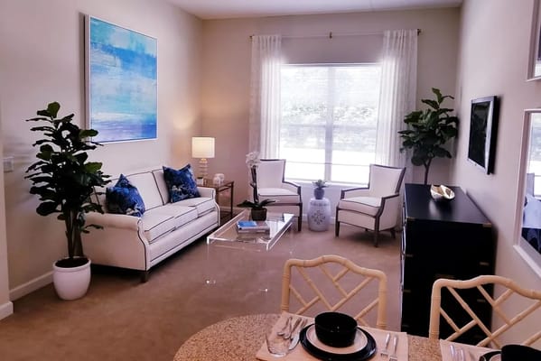 Bright living room with a sofa, chairs, and a dining area.