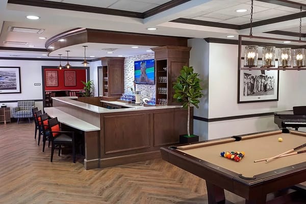 Common area with a pool table and bar at The Bristal Assisted Living
