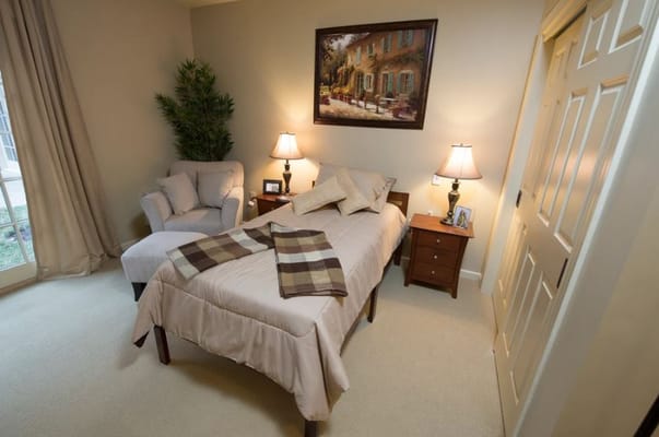 A cozy bedroom featuring a bed, armchair, and bedside tables.