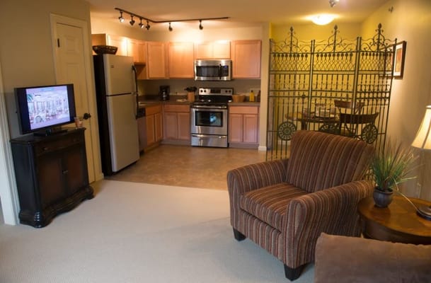 A cozy kitchen and living room with a striped armchair, TV, and dining area.