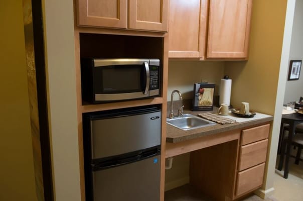 Compact kitchenette featuring a microwave, refrigerator, and sink.