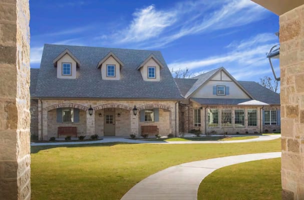 Exterior of a senior living facility with stone architecture and landscaped grounds.