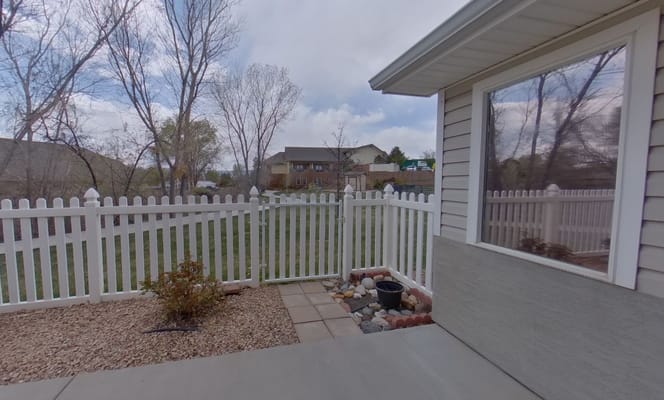 View from the patio showing a fenced yard and trees.